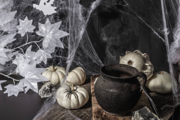 istock Halloween holiday. Festive composition with witch's pot, pumpkins, bat, ghost, spiders, and cobwebs 1349761642