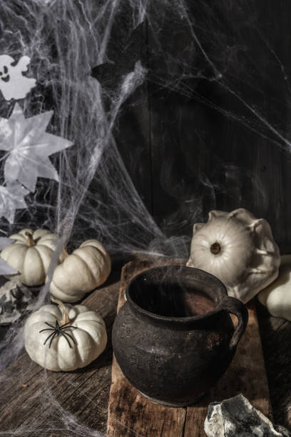 istock Halloween holiday. Festive composition with witch's pot, pumpkins, bat, ghost, spiders, and cobwebs 1349761766