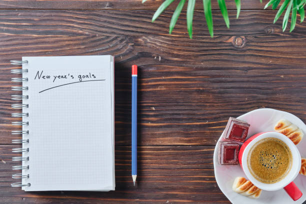 istock notebook with the words new year's goals written on a rustic brown wooden background with a blue and red pencil next to it 1349766165