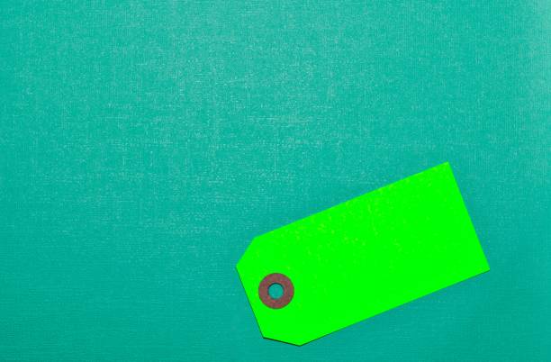 Green blank label tag on a teal cardstock background with copy space, conceptual image.