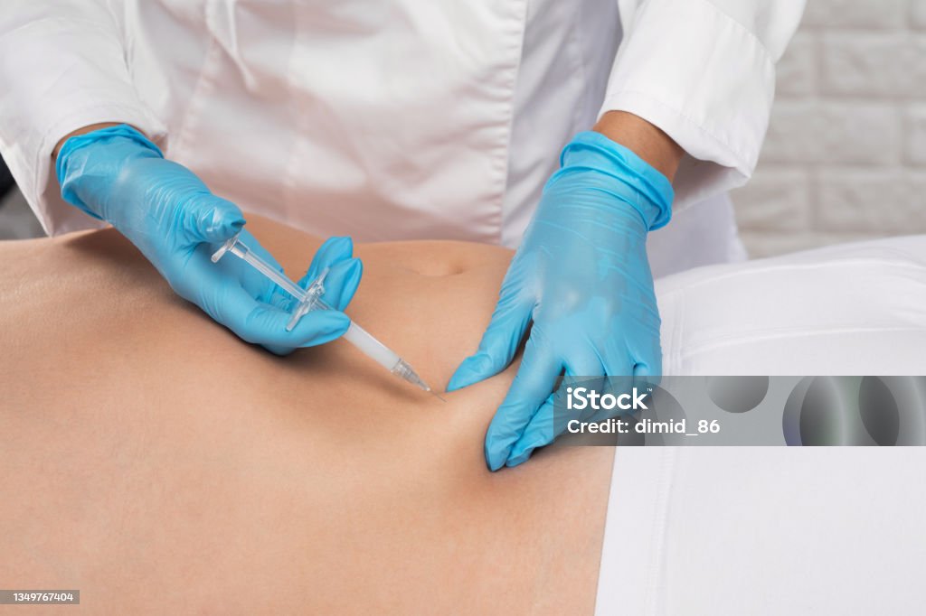 cosmetologist makes lipolytic injections to burn fat on the stomach and waist of a man.  aesthetic cosmetology in a beauty salon.Cosmetology concept. Injecting Stock Photo