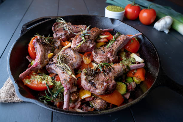 istock Delicious Pan Seared Lambchops in a cast iron skillet on a rustic wood background garnished with vegetables and onion 1349769734