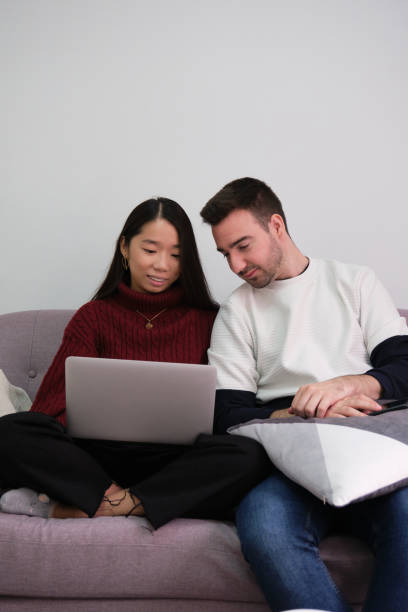 istock Young couple relaxing on a couch at home using a laptop. 1349769824