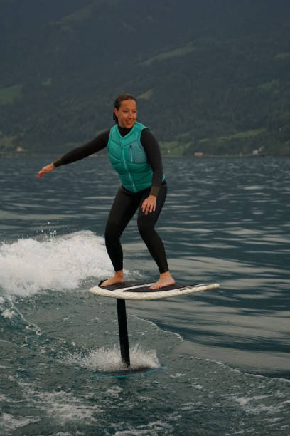 istock Young woman rides hydrofoil surfboard behind boat 1349772947