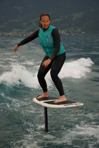istock Young woman rides hydrofoil surfboard behind boat 1349772967