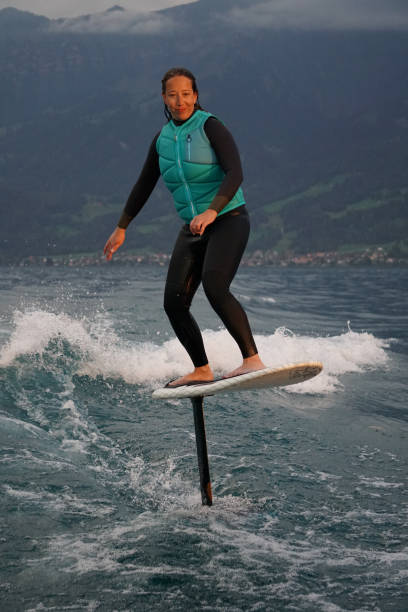 istock Young woman rides hydrofoil surfboard behind boat 1349772972