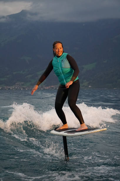 istock Young woman rides hydrofoil surfboard behind boat 1349772976