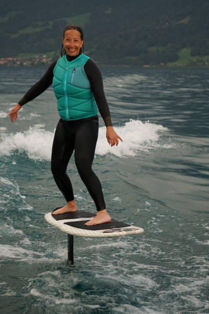 istock Young woman rides hydrofoil surfboard behind boat 1349772995