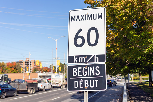 Speed limit road sign in the street with cars, begins 60 km per hour maximum driving in Ottawa city, Canada. Traffic on the road. Rush hour
