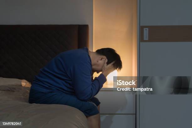 Depressed Lonely Elderly Old Asian Woman People Sitting On Bed In Bedroom At Home Lifestyle On Late Night Insomnia Quarantine Stock Photo - Download Image Now