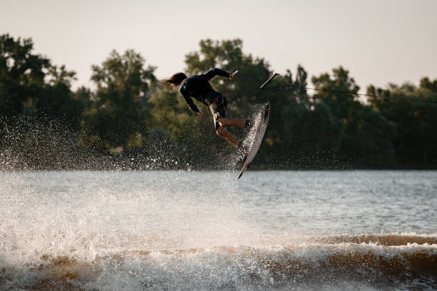 istock active man making trick in jump time with wakeboard and many splashes around 1349783239