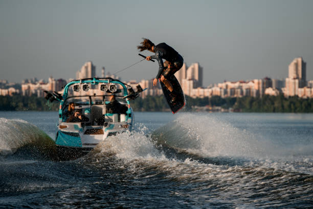 istock energy wakeboarder moving fast behind boat holding rope and masterfully jumping high on splashing river wave. 1349783299