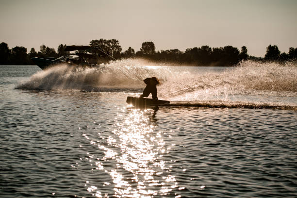 istock energy man holding rope and riding wakeboard and making trick behind motor boat on splashing river waves. 1349783349