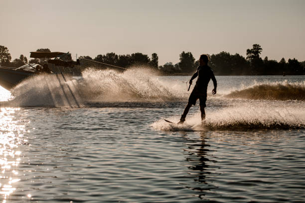 istock handsome man riding wakeboard behind motor boat on splashing river waves. Active and extreme sports 1349783373