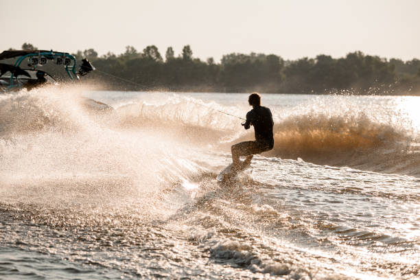 istock Great view of active man riding wakeboard behind motor boat on splashing river waves. Active and extreme sports 1349784005