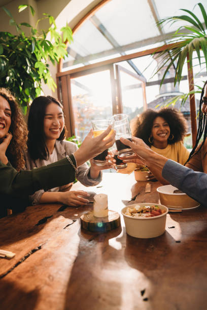 un grupo de amigos está brindando juntos durante una cena - dining people women wine fotografías e imágenes de stock