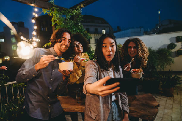 un gruppo di amici si sta facendo un selfie durante una cena sul tetto - laughing night women party foto e immagini stock
