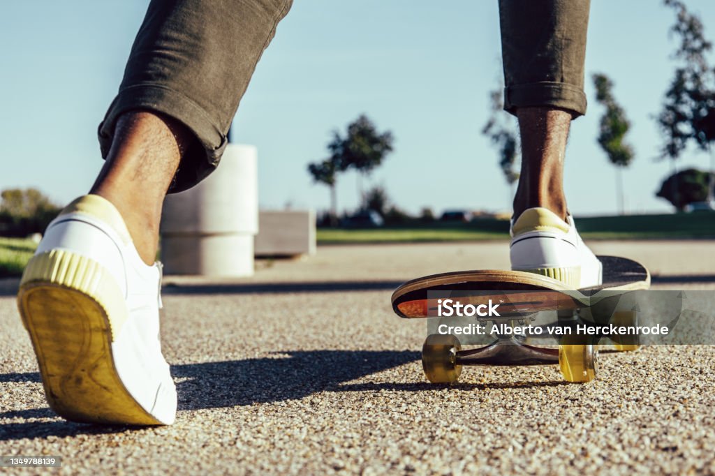 Closeup of black legs riding skateboard in park Skateboarding Stock Photo