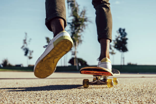 primo piano di gambe nere in sella allo skateboard nel parco - skateboard park extreme sports recreational pursuit skateboarding foto e immagini stock