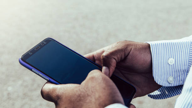 istock Very close-up view of black hands using mobile phone outdoors. 1349788393