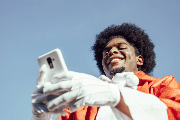 istock African american santa claus using smartphone from below. Sky background 1349788459