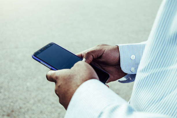istock Very close-up view of black hands using mobile phone outdoors. 1349788552