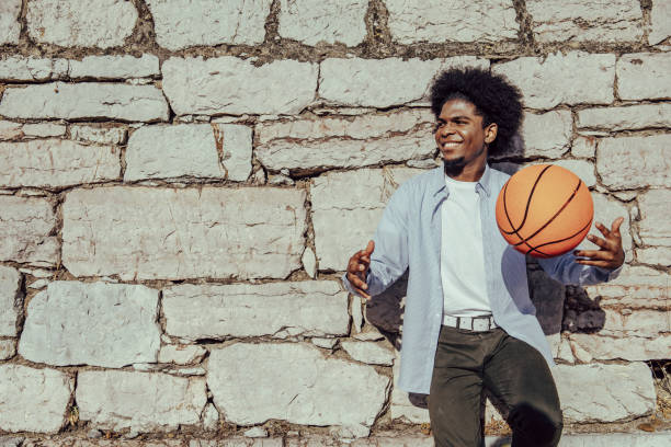 istock Happy afro hair black man with basket ball leaning on wall. Copy space 1349788663