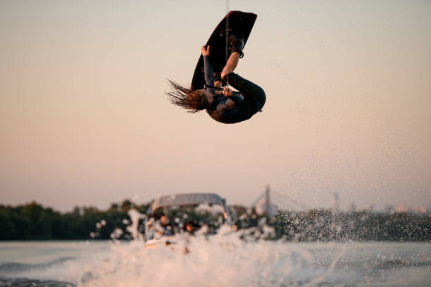 istock male wakeboarder makes extreme stunts jumping and flips on wakeboard over splashing wave 1349791719