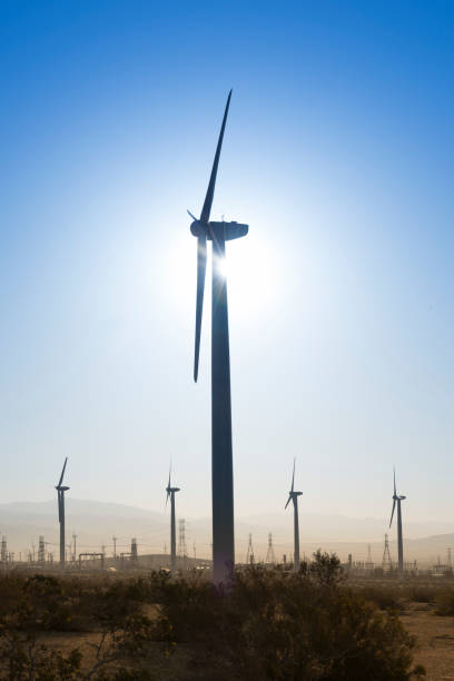 istock Silhouetted windmill with sun and blue sky. 1349791983