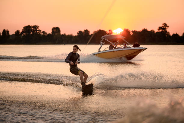 アクティブなウェイクボードトレーニング。男は波の上にケーブルとロールを保持します。 - wakeboarding waterskiing water ski sunset ストックフォトと画像