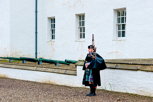 A traditional Scottish bagpiper outside a building in Pitlochry, Scotland, just north of Edinburgh.
