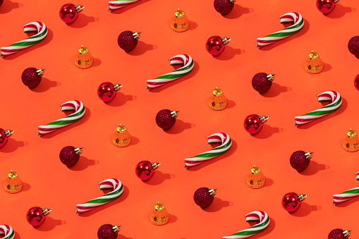 Christmas ornaments and candy canes repetition on orange colored background