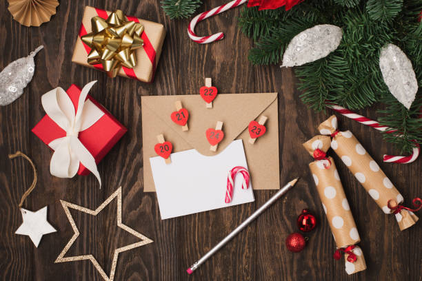 istock Empty white holiday card, red flower poinsettia, Christmas decorations, gift boxes and candy canes on dark wooden background. 1349797421