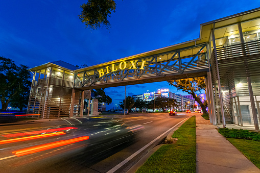 Biloxi, Mississippi, USA - June 30, 2021: Cars pass under Biloxi sign entering the casino district at twilight.