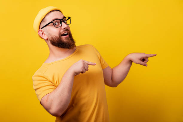 istock smiling bearded man in glasses point index finger 1349802823