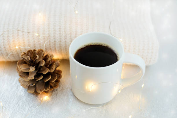 istock White mug of coffee, pine cone and sweater with christmas lights. Winter holidays 1349804321