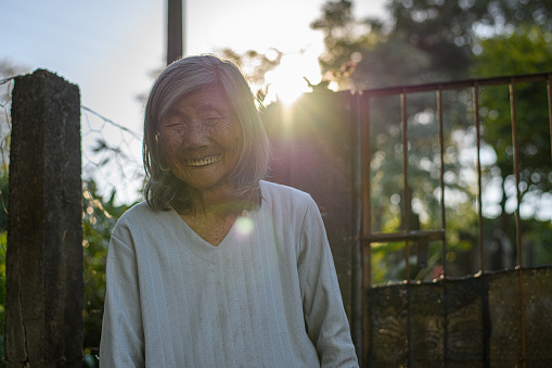 Elderly Japanese woman looking at camera.  Picture at sunset.