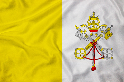 Small paper flag of Vatican City pinned. Isolated on white background. Horizontal orientation. Close up photography. Copy space.