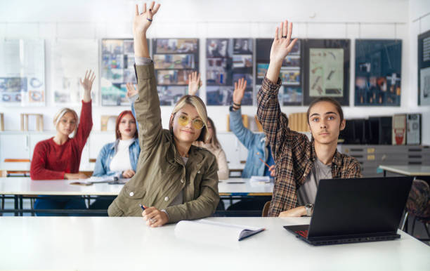 教室で腕を上げた高校生のグループ。 - high school high school student classroom group of people ストックフォトと画像