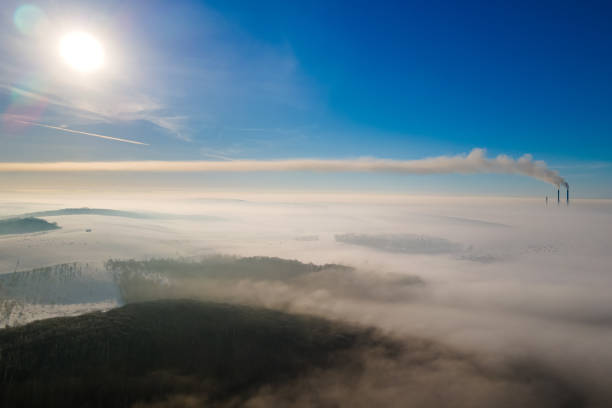 vista aérea da paisagem de inverno com campo nebuloso e tubos de fábrica distantes emmitando o ambiente poluente da fumaça suja preta. - rasto de fumo de avião - fotografias e filmes do acervo