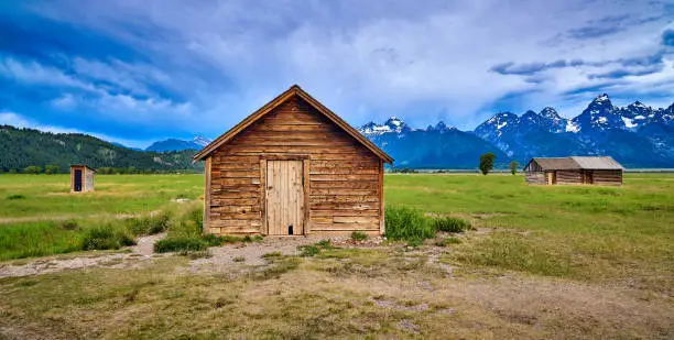Storm clouds with outhouse, pumphouse and granary. Mormon Row, Grand Teton National Park.