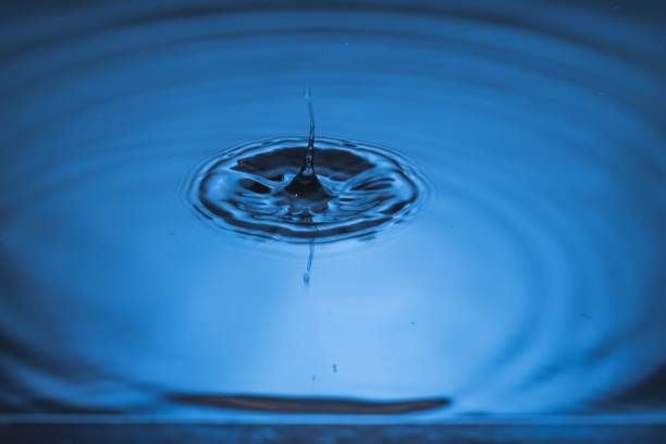 istock Close up view of drops making circles on blue water surface isolated on background 1349813199