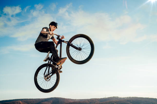 Mountain biker flying through the air after jumping off a ramp stock photo