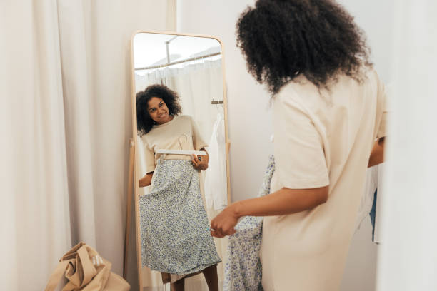 femme élégante essayant des vêtements dans un vestiaire dans une boutique - mirror women dress looking photos et images de collection