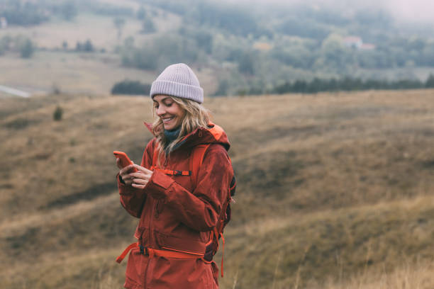 istock Beautiful Smiling Female Hiker Exploring the Mountains, Using her Smartphone to Navigate 1349823042