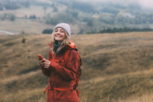 istock Beautiful Smiling Female Hiker Exploring the Mountains, Using her Smartphone to Navigate 1349823046