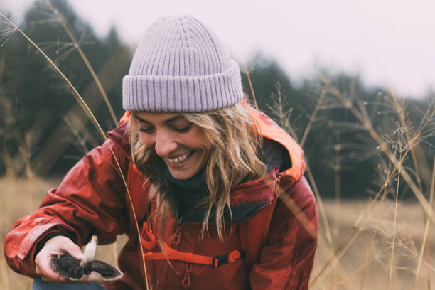 Portrait of a Beautiful Female Nature Lover Picking Mushrooms in the Mountain on a Rainy Day A portrait of a young blonde female hiker picking mushrooms in the meadow on a rainy day splash mountain stock pictures, royalty-free photos & images