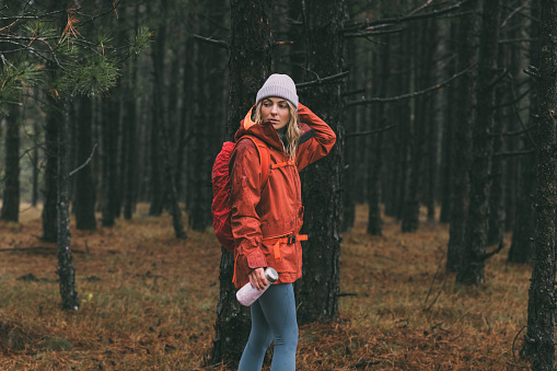 A blonde female adventurer standing in the woods, holding a vacuum flask