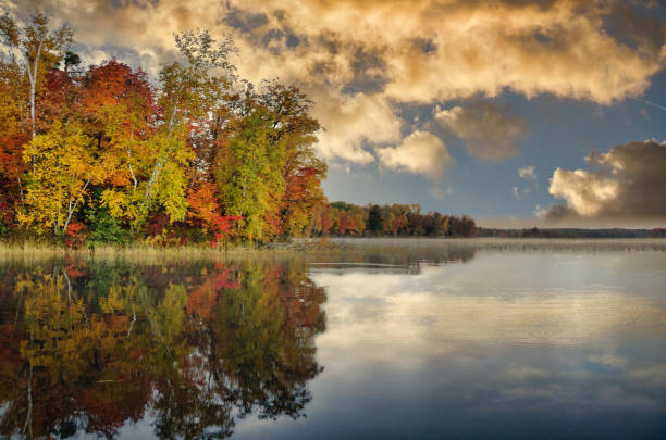 istock Sunset over autumn colored trees reflecting in clear Minnesota lake 1349831658