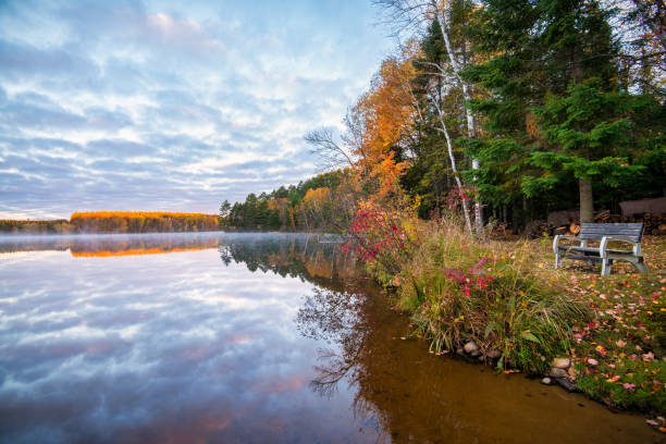 istock Bench on shoreline beautiful autumn splendor 1349832366